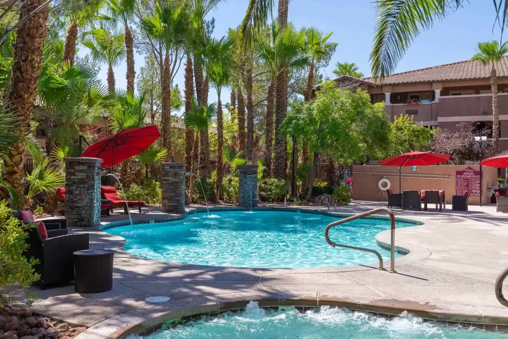 Resort-style pool and spa with red umbrellas and palm trees at The Willows in Las Vegas