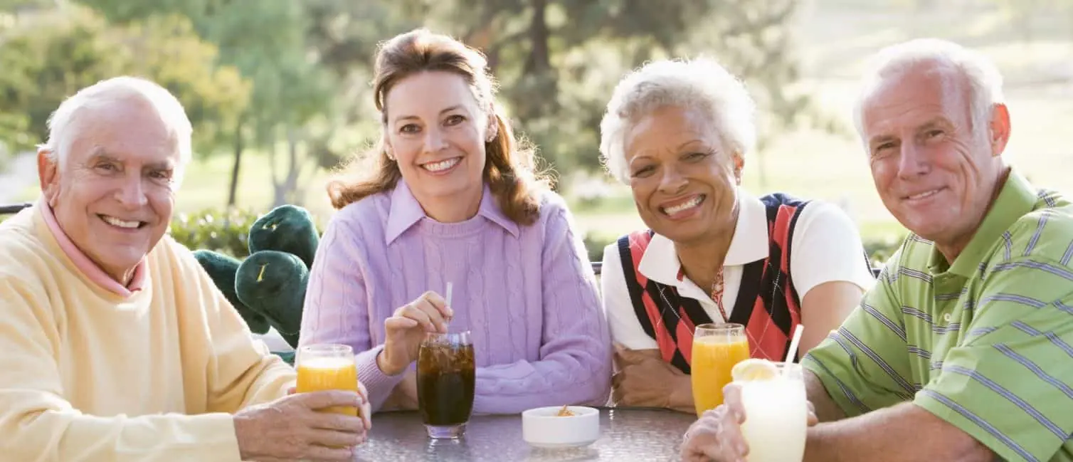 Four seniors enjoying drinks together at an outdoor table