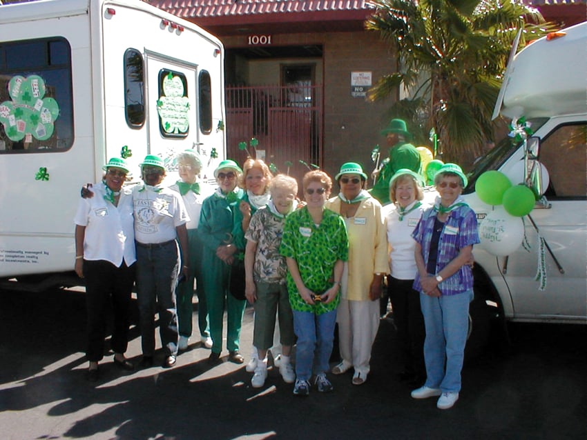 Carefree residents in green hats and shamrocks beside the community bus on St Patrick's Day