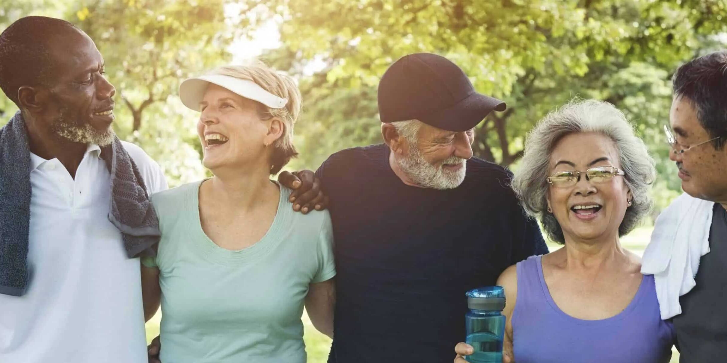Group of five older adults happily walking outdoors in sunlight
